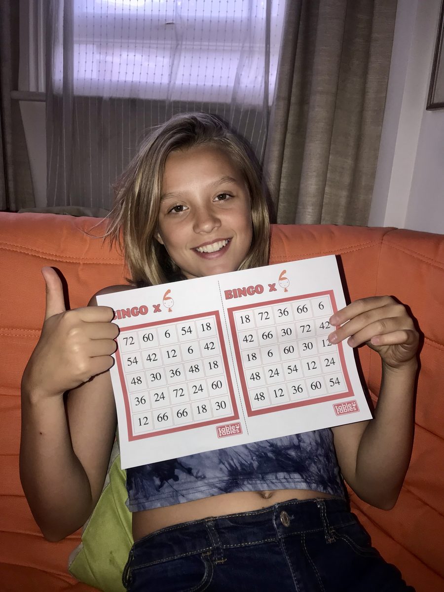 Romy holding a Table Fables bingo worksheet